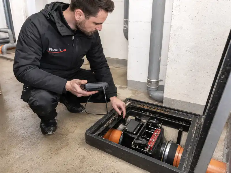 NOMIS Techniker prüft eine Rückstauklappe im Keller